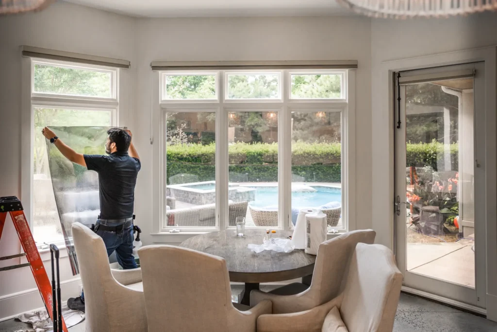 Sun Stoppers installer applying window film in a bright dining room
