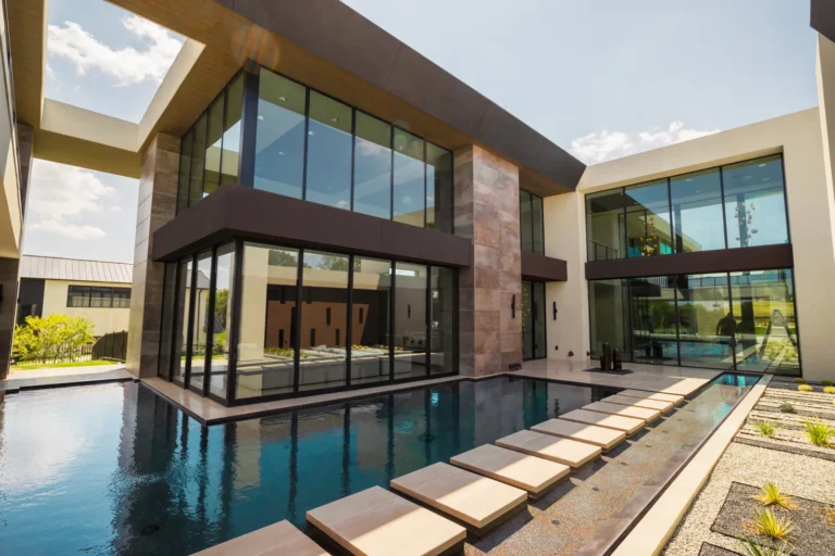 Modern home with large glass windows beside a swimming pool